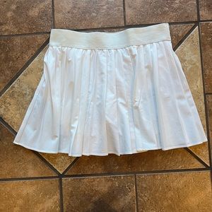 White tessa tennis skirt has shorts underneath stretchy waist band! Size Medium!